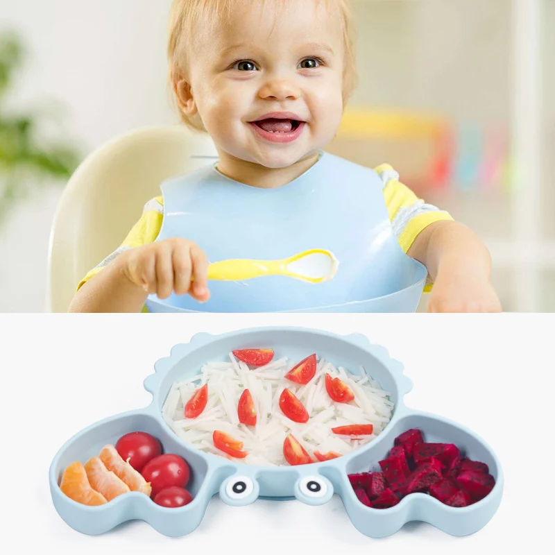 Bébé souriant avec bavoir silicone et assiette crabe à ventouse